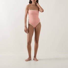 Model wearing Eres pink ribbed strapless one-piece swimsuit with contrast white trim detail