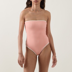 Model wearing Eres pink strapless ribbed swimsuit with contrast white trim detail at bust and leg openings