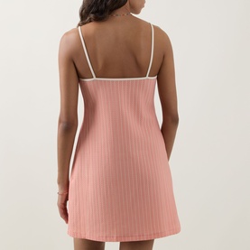Model wearing Eres pink ribbed slip dress cover-up with white trim straps, shown from the back, mini length