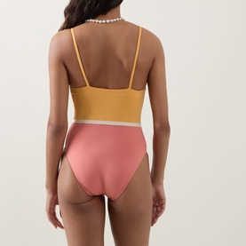 Model wearing Eres pink and yellow two-tone swimsuit, back view, with thin straps and white contrast waistband detail