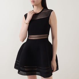 Model wearing Jonathan Simkhai black sleeveless dress with sheer stripe panels at bust, waist and hem, full skirt silhouette.