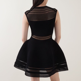 Model wearing Jonathan Simkhai black mini dress with sheer stripe mesh panels at shoulders, waist and hem, flared skirt, back view.