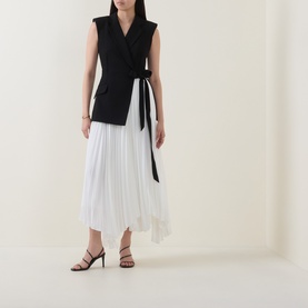 Model wearing Jonathan Simkhai Black Multi dress with sleeveless blazer bodice, black tie waist, and white pleated asymmetric skirt, styled with