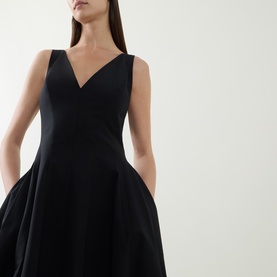 Model wearing Jonathan Simkhai black sleeveless fit-and-flare dress with V-neckline and full skirt with side pockets