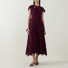 Model wearing Jonathan Simkhai fig midi dress with floral cutwork lace overlay, cap sleeves and handkerchief hem, styled with gold sandals.