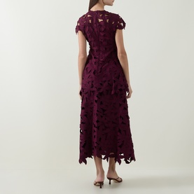 Model wearing Jonathan Simkhai fig floral lace midi dress with cap sleeves and tiered cutwork skirt, back view, styled with tan heels.
