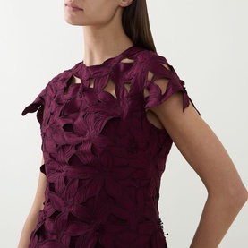 Model wearing Jonathan Simkhai dress in Fig, featuring cutout floral appliqu&eacute; detailing and cap sleeves, close-up detail shot.