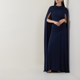 Model wearing Jonathan Simkhai Gown in Midnight, featuring a dramatic floor-length cape and twisted waist detail.