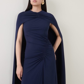 Model wearing Jonathan Simkhai Midnight gown with attached cape sleeves and ruched waist detail, styled with gold earrings