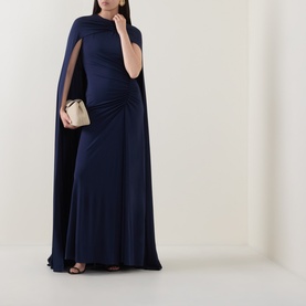 Model wearing Jonathan Simkhai Midnight gown with cape detail, styled with a gold clutch bag and black heeled sandals.