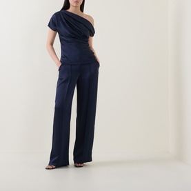 Model wearing Jonathan Simkhai Midnight wide-leg trousers in navy satin fabric, styled with matching off-shoulder top and strappy heels.