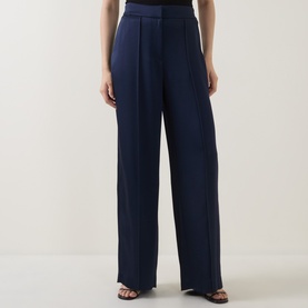 Model wearing Jonathan Simkhai midnight wide-leg trousers with front pleats and high waist in fluid acetate fabric.