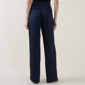 Model wearing Jonathan Simkhai Trousers in Midnight, rear view showing wide-leg silhouette and fluid drape in satin-finish fabric.