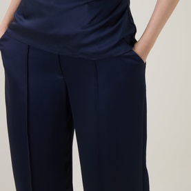 Model wearing Jonathan Simkhai midnight navy wide-leg trousers with front pleats and side pockets, styled with a matching satin top.