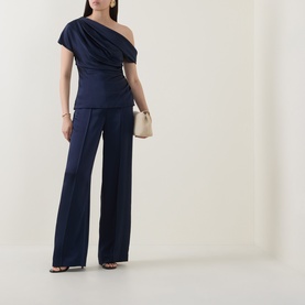 Model wearing Jonathan Simkhai Midnight trousers in wide-leg silhouette, styled with matching one-shoulder top and strappy sandals.