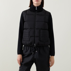 Model wearing Moncler black quilted cardigan with puffer front panel, high neck, and knit sleeves, styled with matching black trousers