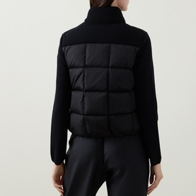Model wearing Moncler black cardigan, back view, quilted padded body panel with knit collar and sleeves, styled with black trousers
