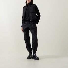 Model wearing Moncler black cardigan with utility-style jacket, styled with matching black cargo trousers and chunky black boots