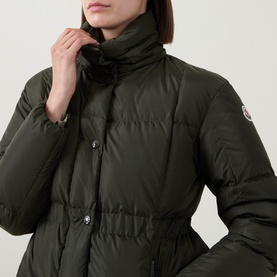 Model wearing Moncler green quilted down jacket with high collar, snap button fastening and cinched waist detail.