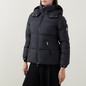 Model wearing Moncler black padded down jacket with detachable hood, zip pockets and logo arm badge, styled with black skirt.