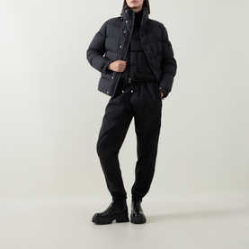 Model wearing Moncler black quilted down puffer jacket, styled with matching black trousers and chunky black boots.