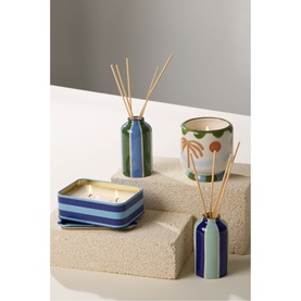 Paddywax A Dopo Eye Ceramic Diffuser in blue stripe pattern with natural reeds, styled alongside matching candle and diffuser set on stone risers