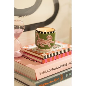 Paddywax A Dopo Tiger Ceramic Candle in green with pink tiger motif and black and white rim, styled on stacked books with pink hourglass