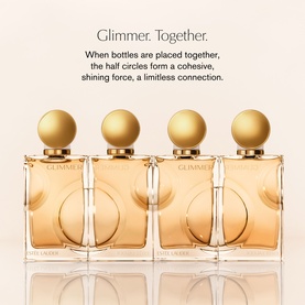 Estee Lauder EDP collection of four gold-capped amber glass bottles arranged together, gold circular embossed detail, cream background with campaign