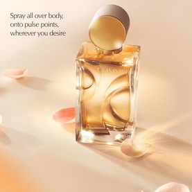 Est&eacute;e Lauder EDP fragrance bottle with gold-toned sculpted glass design, open cap, on a soft peach background with scattered petals