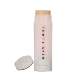 Fenty Skin lip care balm stick in white packaging with cap removed, showing nude-toned product tip