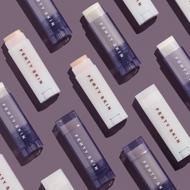 Fenty Skin Lip Care sticks in light and dark shades, arranged in a repeating diagonal pattern on a purple background