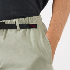 Model wearing Gramicci G-Chinos in Dried Sage, close-up of elasticated waistband, black adjustable belt and logo patch detail.