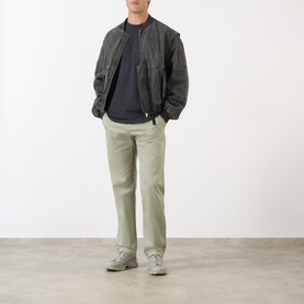 Model wearing Gramicci G-Chinos in Dried Sage, straight-cut cotton trousers with elasticated waistband, styled with dark bomber jacket and grey