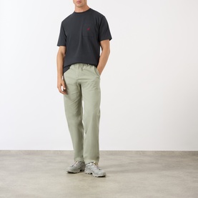 Model wearing Gramicci One Point Chest Pocket T-Shirt in black, styled with sage green trousers and grey trainers.