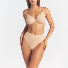 Model wearing Skims beige Full Cup Bra with thin straps, styled with matching beige high-cut briefs.