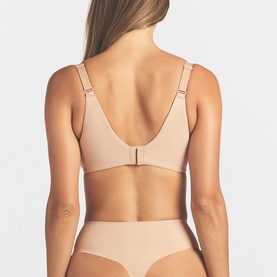 Model wearing Skims Full Cup Bra in beige, back view showing low scoop back, hook fastening, and adjustable straps, styled with matching briefs.