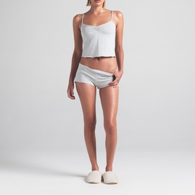 Model wearing Skims light heather grey pyjama cami top and shorts set, styled with white slip-on shoes