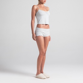 Model wearing Skims light heather grey cami top and shorts pyjama set, styled with cream slippers