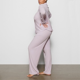 Model wearing Skims Pyjamas in Iris Mica, long-sleeve top and wide-leg trousers, side profile view