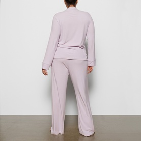 Model wearing Skims Pyjamas in Iris Mica, shown from behind in a relaxed long-sleeve top and wide-leg trousers as a coordinating set.