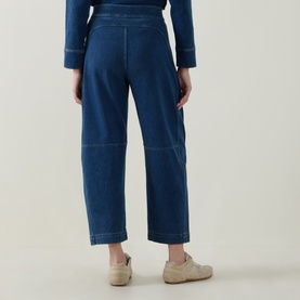 Model wearing Spanx Denim Barrel Leg Track Pants in dark blue with tobacco stitching, barrel-leg silhouette and cropped length, rear view