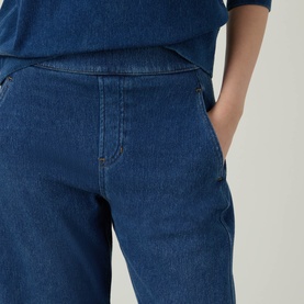 Model wearing Spanx Denim Barrel Leg Track Pants in dark blue with tobacco stitching, high-rise waistband and side pockets, styled with a blue top