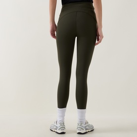 Model wearing dark olive green high-waisted cropped leggings, styled with white ankle socks and grey trainers, rear view.