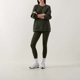 Model wearing dark olive green sweatshirt and matching leggings, styled with white chunky trainers and white socks