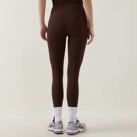 Model wearing dark brown high-waist leggings, styled with white ankle socks and grey trainers, rear view
