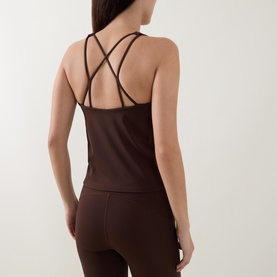 Model wearing dark brown strappy cross-back sports cami top with matching high-waist leggings, rear view.