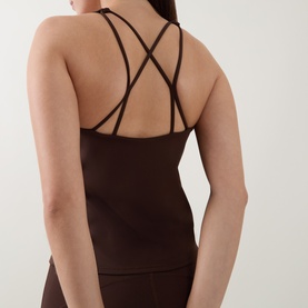 Model wearing dark brown sleeveless top with cross-back double strap detail, styled with matching brown wide-leg trousers