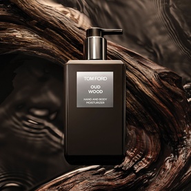 Tom Ford Oud Wood Hand and Body Moisturiser in dark glass pump bottle, styled against textured dark wood bark background.
