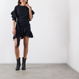 Model wearing Isabel Marant Etoile Melicia Ruffle Mini Dress in black with ruffled sleeves and asymmetric skirt, styled with black cowboy boots