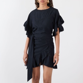 Model wearing Isabel Marant Etoile Melicia Ruffle Mini Dress in black with ruffled sleeves, tie waist, and ruched skirt. Styled with gold earrings.